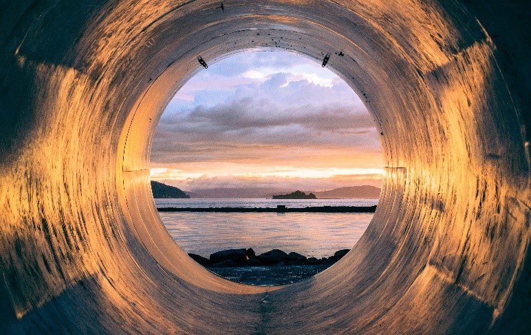 A view of the ocean from inside a pipe.