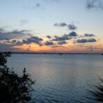 A view of the ocean at sunset with clouds in the sky.